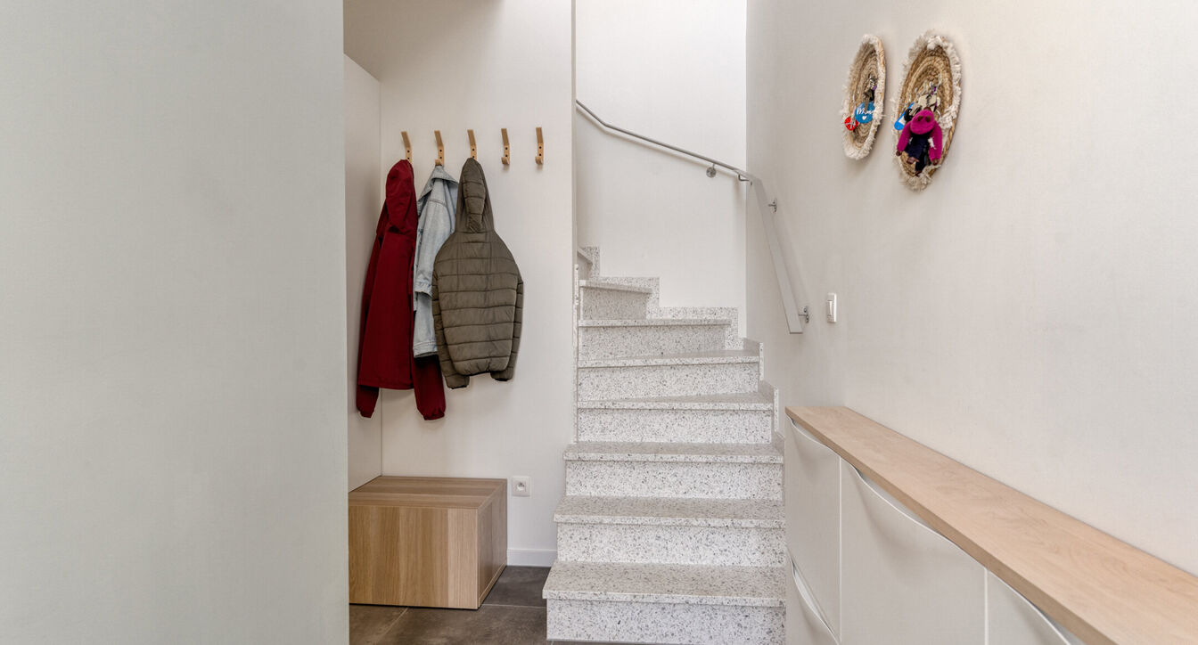 Deze stijlvolle en energiezuinige woning combineert hedendaags wooncomfort met een praktische indeling en een aangename buitenruimte.
Bij het binnenkomen verwelkomt de inkomhal je met een apart gastentoilet. Vervolgens kom je in de ruime leefruimte met o
