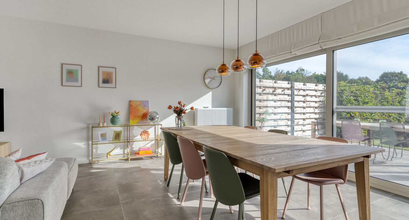 Deze stijlvolle en energiezuinige woning combineert hedendaags wooncomfort met een praktische indeling en een aangename buitenruimte.
Bij het binnenkomen verwelkomt de inkomhal je met een apart gastentoilet. Vervolgens kom je in de ruime leefruimte met o