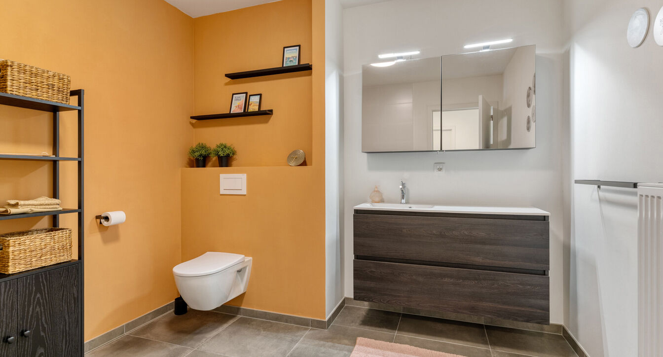 Deze stijlvolle en energiezuinige woning combineert hedendaags wooncomfort met een praktische indeling en een aangename buitenruimte.
Bij het binnenkomen verwelkomt de inkomhal je met een apart gastentoilet. Vervolgens kom je in de ruime leefruimte met o