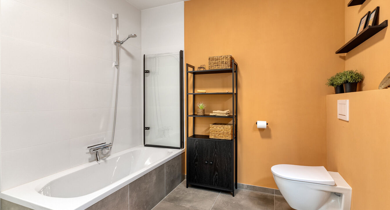 Deze stijlvolle en energiezuinige woning combineert hedendaags wooncomfort met een praktische indeling en een aangename buitenruimte.
Bij het binnenkomen verwelkomt de inkomhal je met een apart gastentoilet. Vervolgens kom je in de ruime leefruimte met o